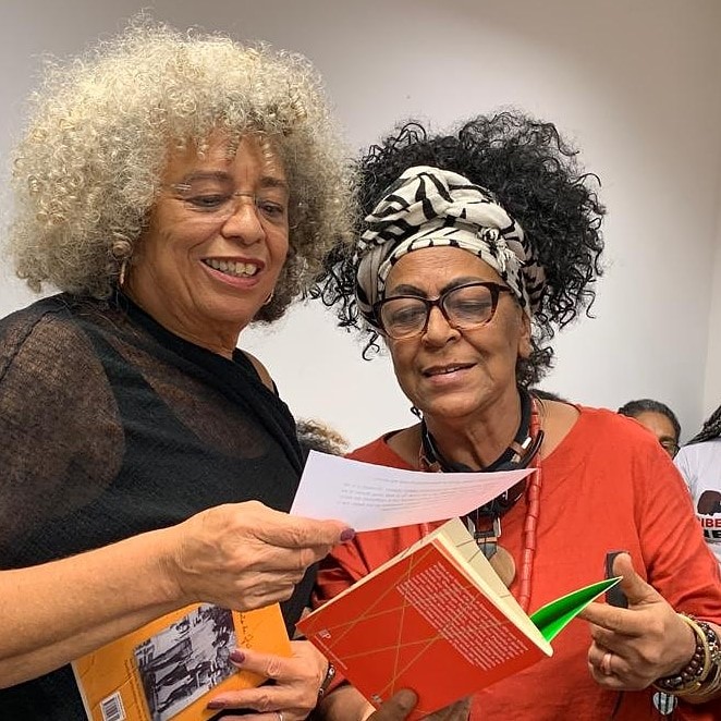 A escritora Vilma Piedade (na direita), mostra o livro Dororidade para a filósofa americana Angela Davis, em um encontro de mulheres pretas, em 2019. (esquerda) arquivo pessoal da escritora